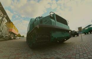 Photo of a Russian green armored car on a caterpillar track among the railway trains. Strong distortion from the fisheye lens