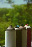 A few used aerosol paint sprayers lie on the windowsill in the workshop of a graffiti artist. The concept of street art and illegal drawing on the walls. Youth hobby photo