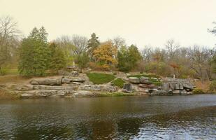 Beautiful Nature Autumn landscape with lake. Scenery view on autumn city park with golden yellow foliage in cloudy day photo