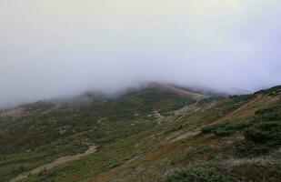 Morning view from the Dragobrat mountain peaks in Carpathian mountains, Ukraine. Cloudy and foggy landscape around Drahobrat Peaks photo