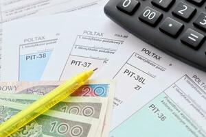 Declaration of the amount of earned income or incurred loss, PIT-36, PIT-36L, PIT-37 and PIT-38 tax forms on accountant table with pen and calculator photo