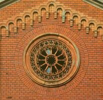 Texture front part of an ancient brick crypt with a round patterned carved window in the cemetery photo