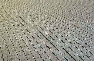 Gray color paving slabs in the pedestrian street sidewalk. Rough cobblestone pattern with many square shaped stones photo