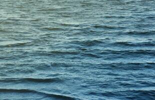 The raging waters of the river. Top view background texture of the raging elements. White foam on blue waving water photo