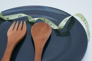 spoon and fork on the plate with measuring tape. diet concept for a healthy lifestyle photo