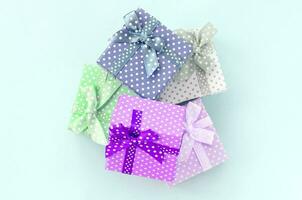 Pile of a small colored gift boxes with ribbons lies on a violet background. Minimalism flat lay top view photo