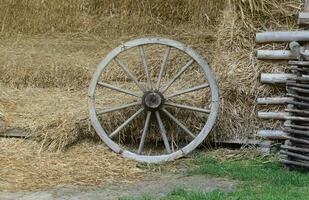 Place with stacks of hay cubes and rustic wooden wheels of old cart photo