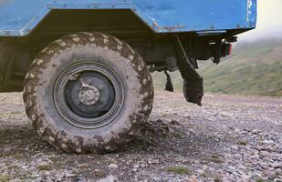 Wheel closeup in a countryside landscape with a mud road. Off-road 4x4 suv automobile with ditry body after drive in muddy road photo