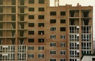 View of a large construction site with buildings under construction and multi-storey residential homes. Tower cranes in action on blue sky background. Housing renovation concept photo