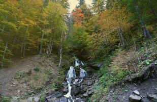 A mountain waterfall flows over the rocks. Waterfall cascade on mossy rocks photo