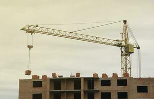 View of a large construction site with buildings under construction and multi-storey residential homes. Tower cranes in action on blue sky background. Housing renovation concept photo