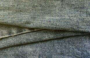 Detailed abstract texture of dark blue denim cloth. Background image of old used denim trousers fabric photo