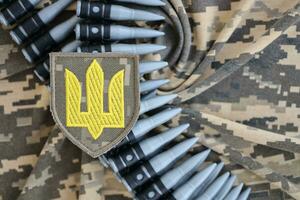 Ukrainian army symbol on machine gun belt lies on ukrainian pixeled military camouflage photo