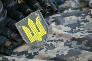 Ukrainian army symbol on machine gun belt lies on ukrainian pixeled military camouflage photo