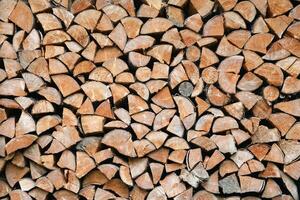 Firewood stacked near the wooden wall of old hut. Many chopped logs of firewood photo