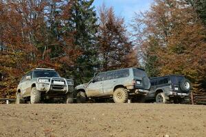 Automobile in a countryside landscape with a mud road. Off-road 4x4 suv automobile with ditry body after drive in muddy road photo