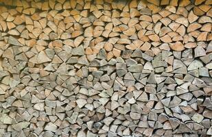 Firewood stacked near the wooden wall of old hut. Many chopped logs of firewood photo