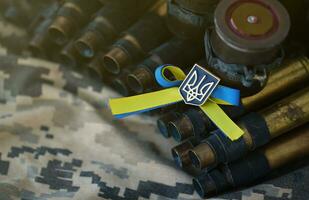 Ukrainian symbol on machine gun belt lies on ukrainian pixeled military camouflage photo