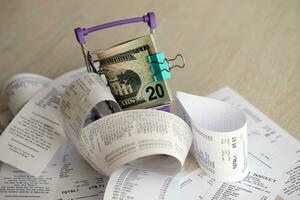 US dollars bunch in shopping trolley surrounded by many paper receipts photo