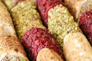 Rolls of turkish delight with many different flavors and fillings close up on table of vendors market photo