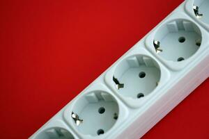 White electrical multi plug extender with european socket on bright red background photo