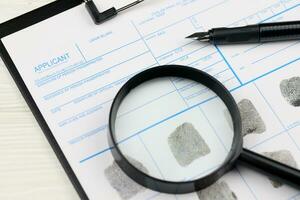 Fingerprints card police form on A4 tablet lies on office table with pen and magnifying glass photo