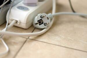 Overloaded power boards. Power strips with different electrical plugs on white floor photo