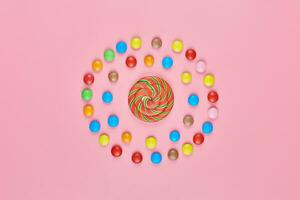 Sweet lollipop and candy on pink background photo