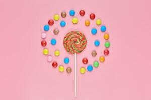 Sweet lollipop and candy on pink background photo