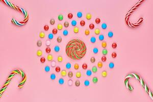 Sweet lollipops and candy canes on pink background photo