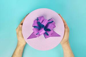 Round gift box with bow in hands photo