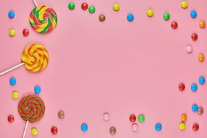 Sweet candy copy space frame with lollipops on pink background photo