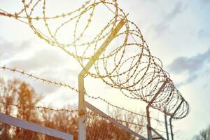 Barbed wire on fence restrict access to the restricted area. photo