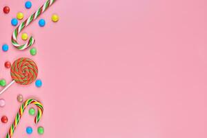 Sweets, lollipop and candy canes on pink background photo