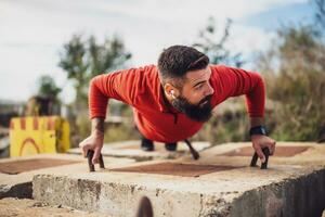 joven hombre es hacer ejercicio exterior. él es haciendo Lagartijas. foto