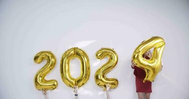 a woman in a red dress holding a gold balloon with the number 2024 video