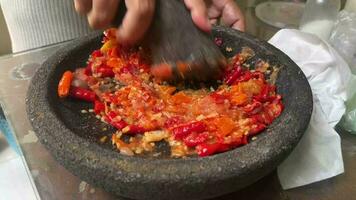 sambal bawang dans le fabrication en utilisant traditionnel outil appelé oulékan. sambal bawang est une délicieux traditionnel sauce de Indonésie fabriqué de piments et Ail. video