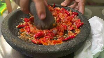 sambal bawang in de maken gebruik makend van traditioneel gereedschap gebeld oekan. sambal bawang is een heerlijk traditioneel saus van Indonesië gemaakt van pepers en knoflook. video