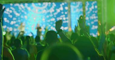 lento movimiento el luces parpadeo desde el música etapa y el personas levantamiento su manos bailando a el pulsante música de esta música festival retenida gratis de cargar en el público parque de Asia. video