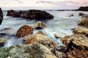 rocas y agua a puesta de sol en el playa foto