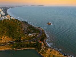 Panoramic coastal Vung Tau view from above, with waves, coastline, streets, coconut trees, Mount Nho in Vietnam behind the statue of Christ the King photo
