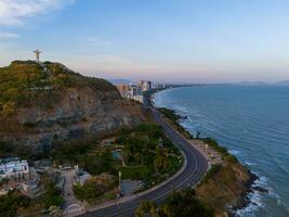 Panoramic coastal Vung Tau view from above, with waves, coastline, streets, coconut trees, Mount Nho in Vietnam behind the statue of Christ the King photo