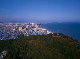 Panoramic coastal Vung Tau view from above, with waves, coastline, streets, coconut trees, Mount Nho in Vietnam behind the statue of Christ the King photo