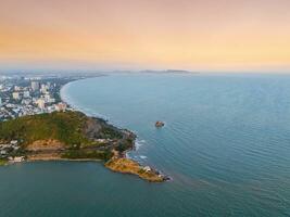 Panoramic coastal Vung Tau view from above, with waves, coastline, streets, coconut trees, Mount Nho in Vietnam behind the statue of Christ the King photo