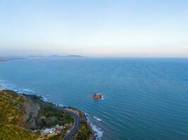 Panoramic coastal Vung Tau view from above, with waves, coastline, streets, coconut trees, Mount Nho in Vietnam behind the statue of Christ the King photo