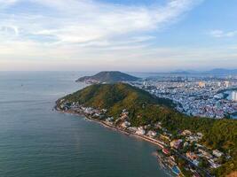 Panoramic coastal Vung Tau view from above, with waves, coastline, streets, coconut trees, Mount Nho in Vietnam behind the statue of Christ the King photo