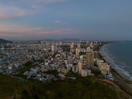 Panoramic coastal Vung Tau view from above, with waves, coastline, streets, coconut trees, Mount Nho in Vietnam behind the statue of Christ the King photo