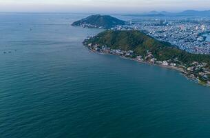 Panoramic coastal Vung Tau view from above, with waves, coastline, streets, coconut trees, Mount Nho in Vietnam behind the statue of Christ the King photo