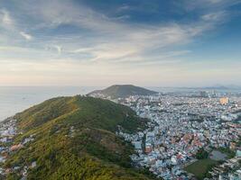 Panoramic coastal Vung Tau view from above, with waves, coastline, streets, coconut trees, Mount Nho in Vietnam behind the statue of Christ the King photo