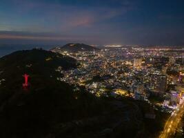 Panoramic coastal Vung Tau view from above, with waves, coastline, streets, coconut trees, Mount Nho in Vietnam behind the statue of Christ the King photo